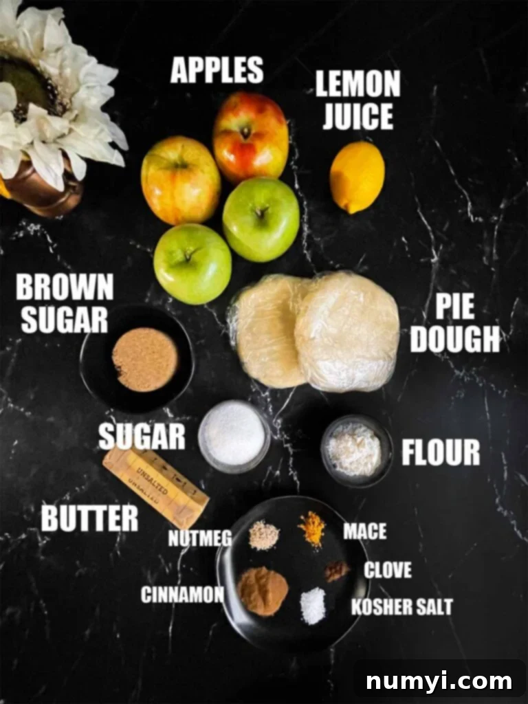 Ingredients for apple pie, including fresh apples, butter, sugar, and spices, on a dark surface.