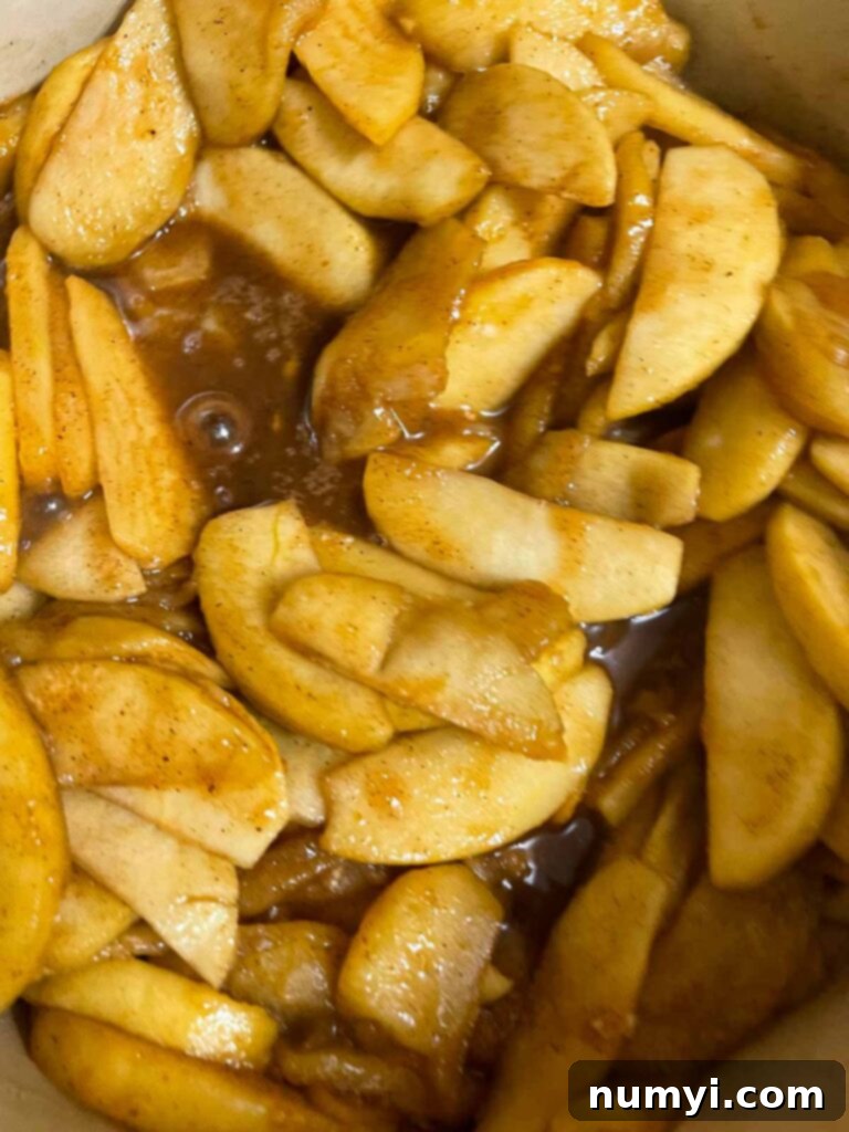 Cooked apple pie filling simmering gently in a dutch oven.