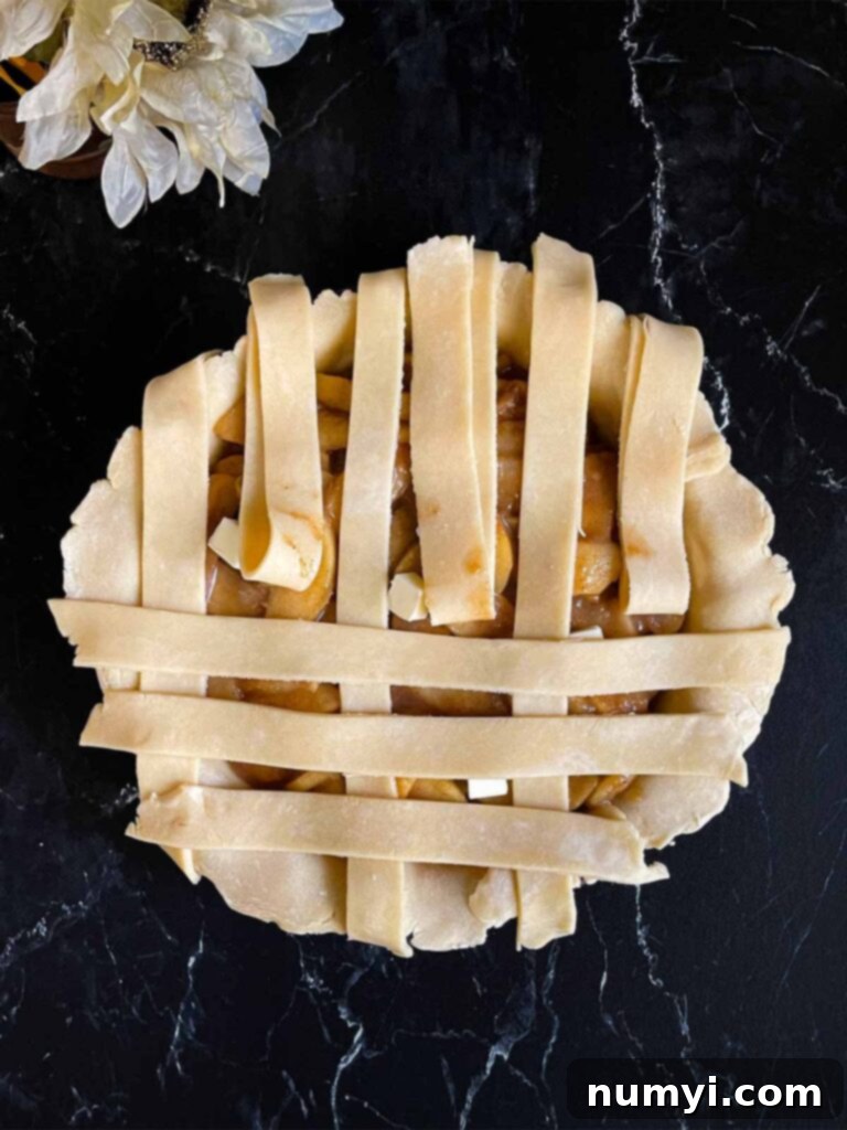 Pie dough strips intricately woven over the apple pie filling, forming a lattice.