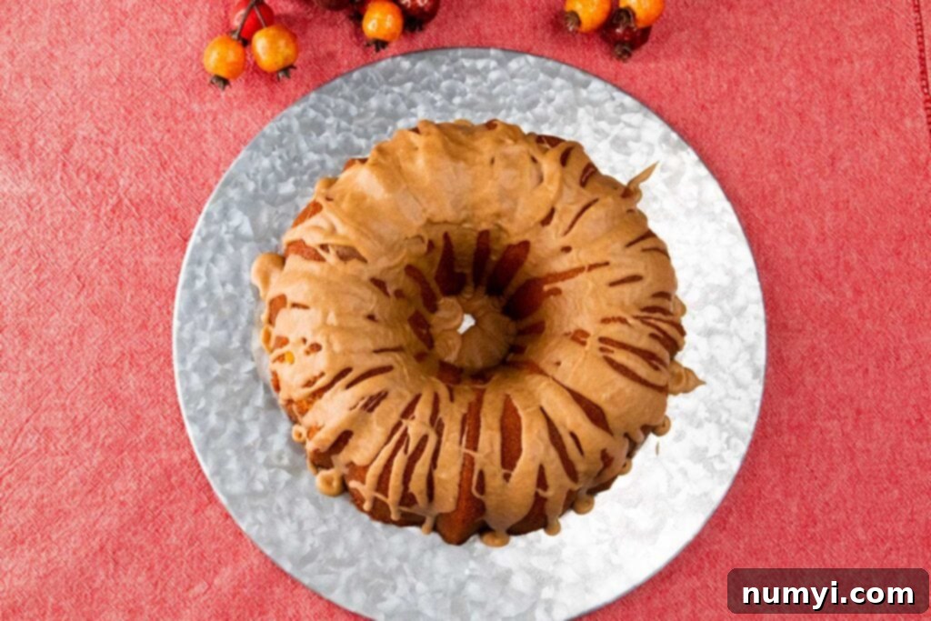 A beautifully presented apple cider pound cake on a silver plate, glistening with glaze.