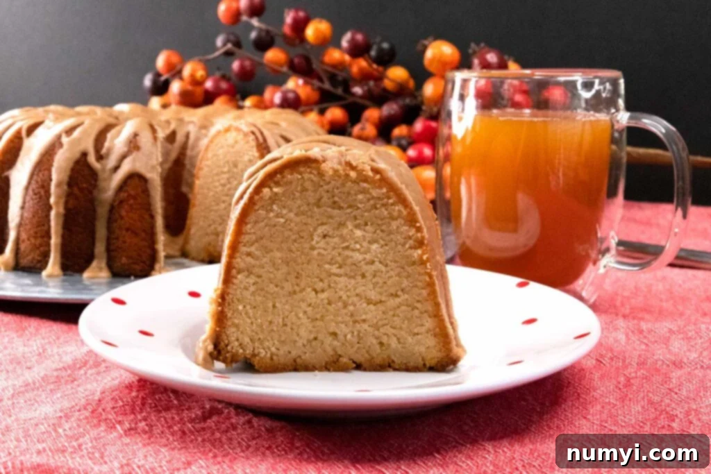 A delightful slice of apple cider pound cake with glaze, served on a white plate with red dots.