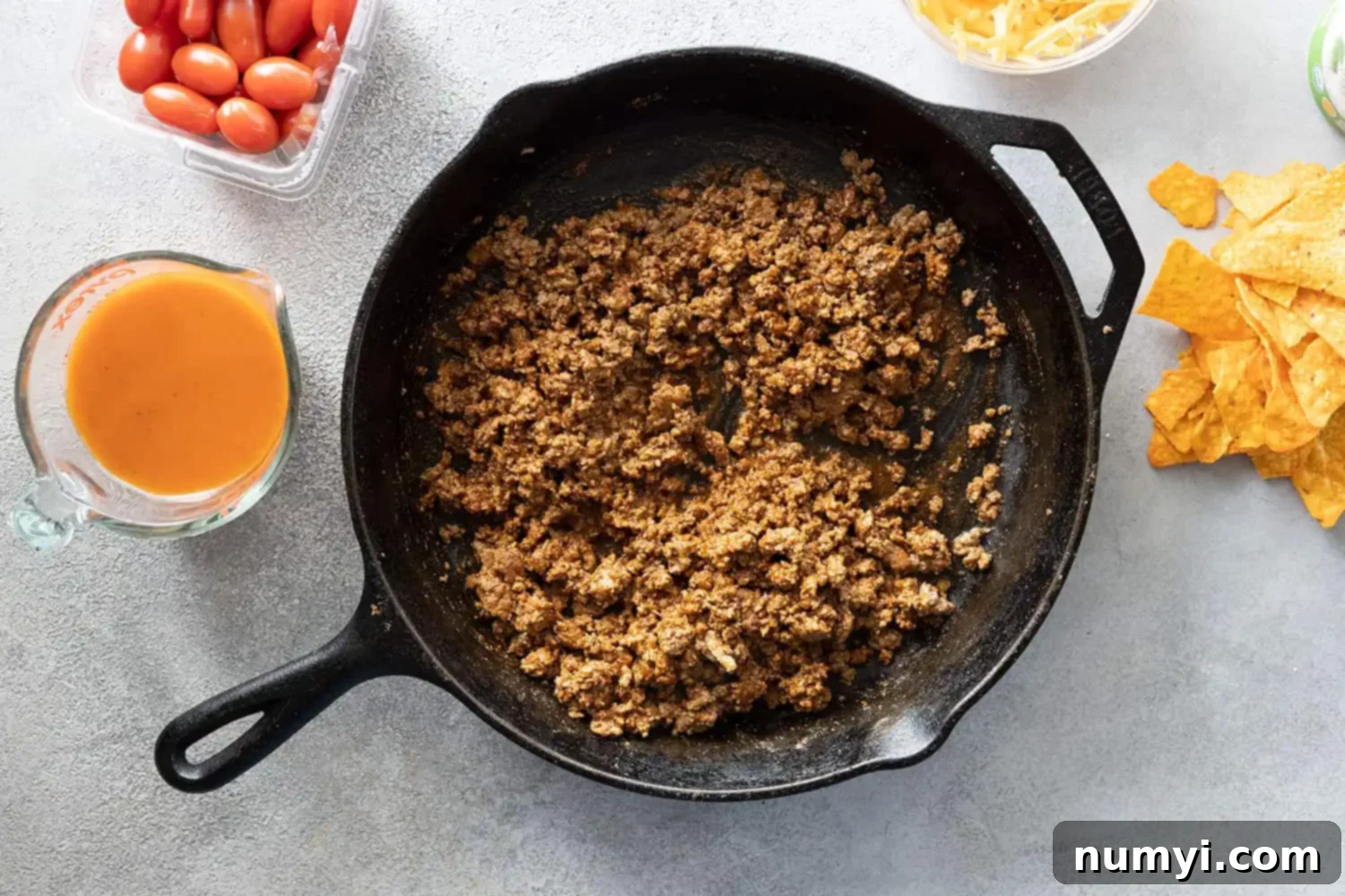 Overhead picture of taco meat in a cast iron skillet. Other ingredients off to the side.