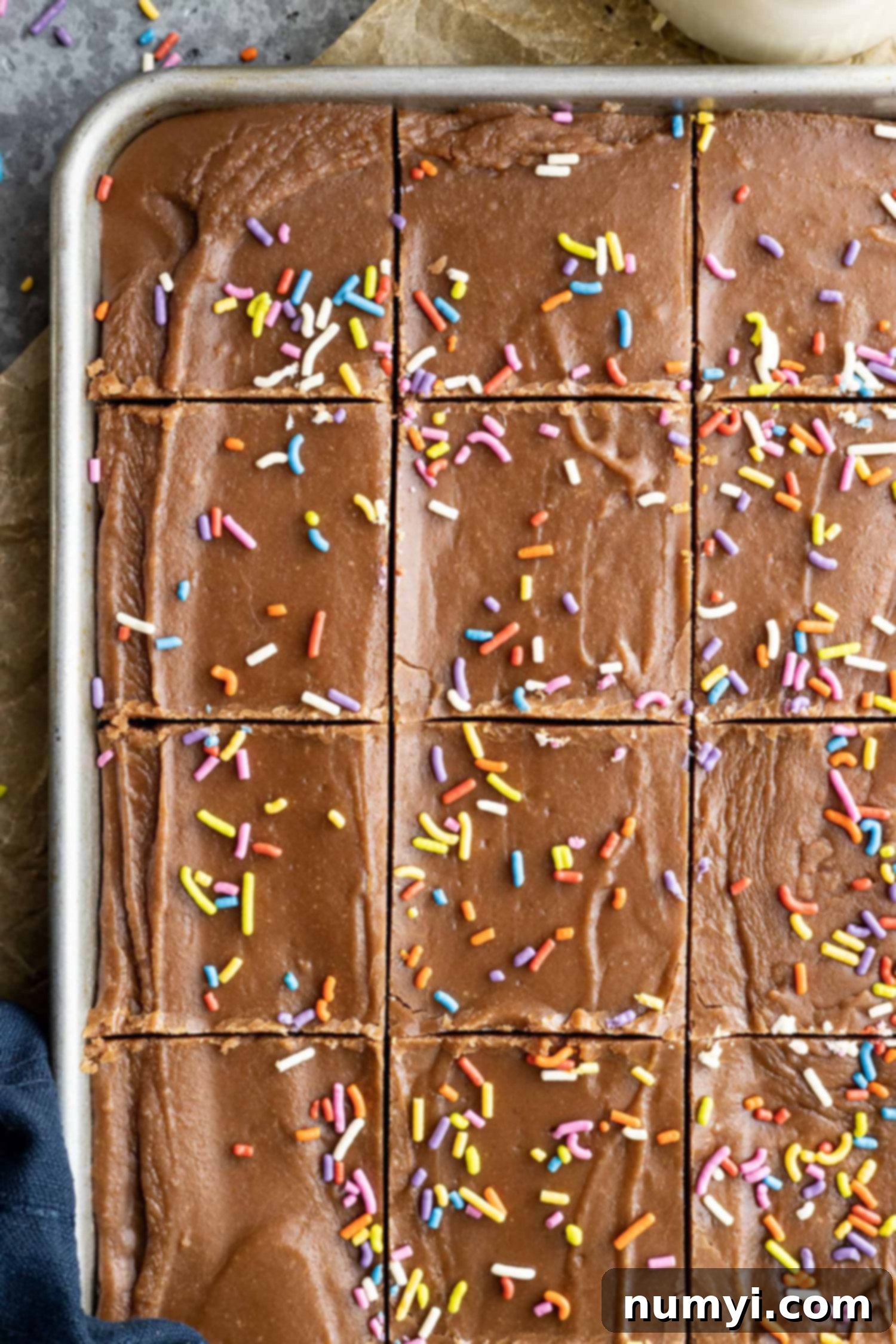 Overhead shot of freshly baked frosted brownies, still warm and fudgy, cut directly in the baking pan, showcasing their inviting texture.