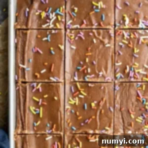 Close-up of a stack of three frosted brownies, showing their thick, fudgy texture and glossy chocolate frosting.