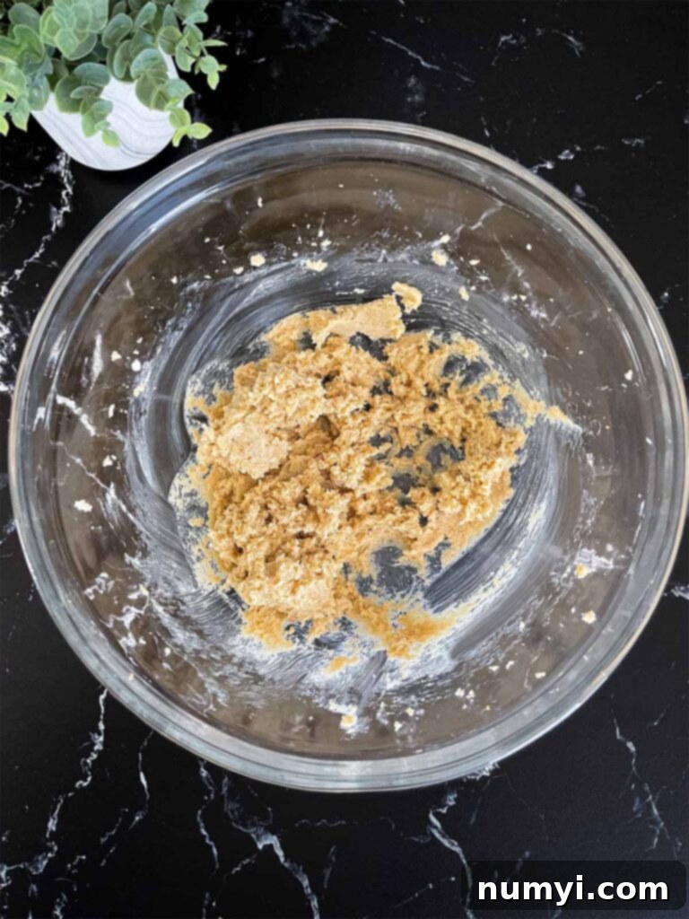 Sugars and butter being creamed together in a glass mixing bowl for the almond joy cookies recipe, showing a light and fluffy texture.