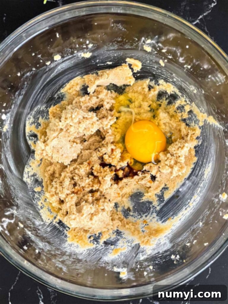 Egg and vanilla extract carefully added to the creamed butter and sugar mixture for almond joy cookies, ready for mixing.