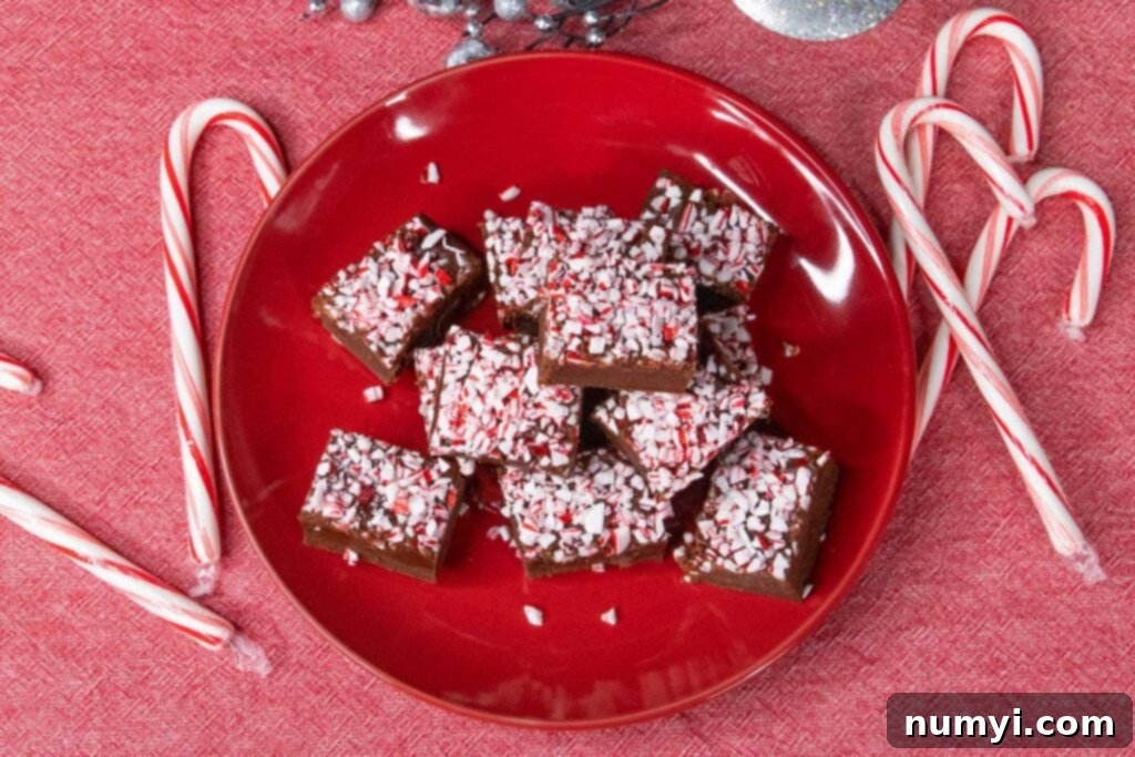 Peppermint fudge on a red plate with scattered candy canes.