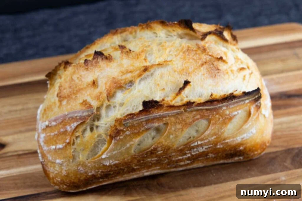A perfectly baked loaf of sourdough bread, golden and inviting, resting on a wooden cutting board.