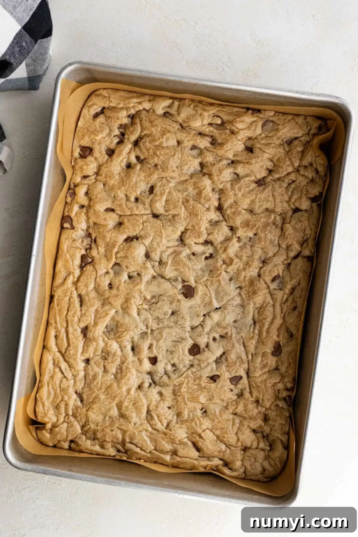 Overhead view of freshly baked chocolate chip cookie bars, golden brown and still warm, cooling in the baking pan.