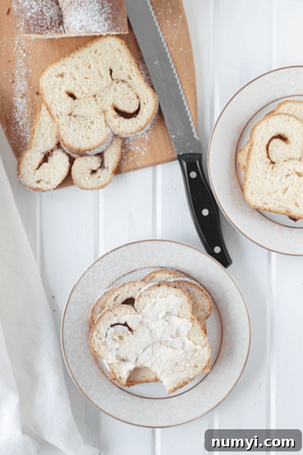 Warm slices of cinnamon swirl bread casually arranged on a table setting, with one slice generously coated in melted butter, inviting a delicious bite.