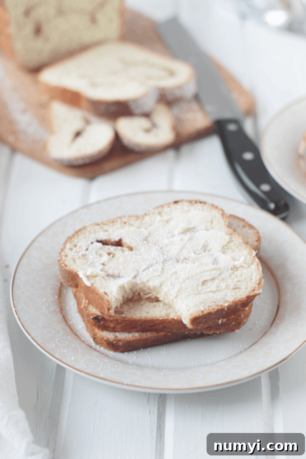 A delicious slice of cinnamon swirl bread with a bite taken out, generously slathered in butter, showcasing its fluffy texture and perfect swirl.