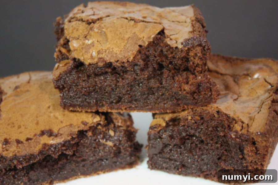 Perfect brownies stacked on a white plate.