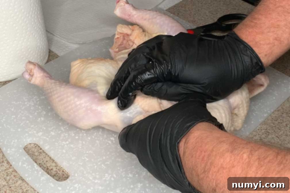 Cracking the breastbone of a chicken, a crucial step for achieving a flat spatchcocked bird ready for the smoker.