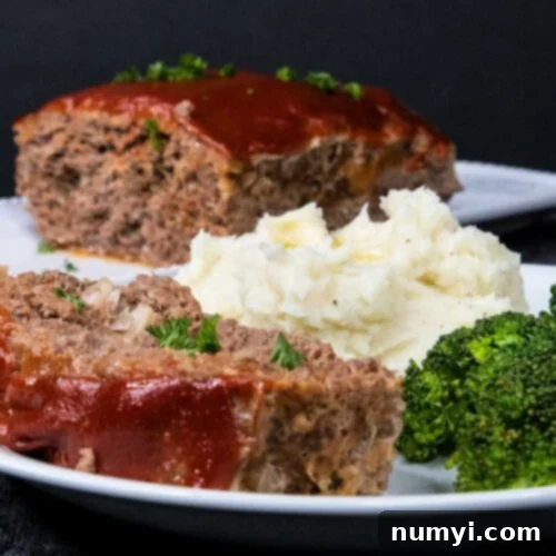 Effortless Weeknight Meatloaf 7 Meatloaf with mashed potatoes and broccoli on a white plate, served hot and garnished.