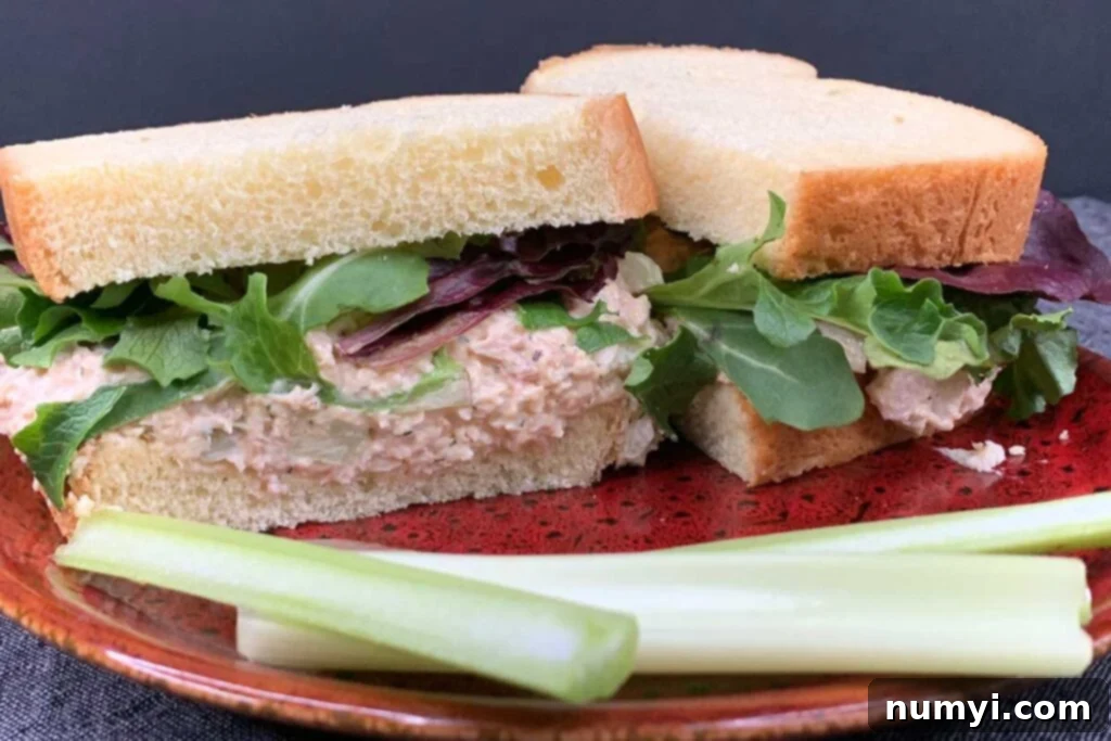 Signature Smoked Chicken Salad 2 Smoked chicken salad sandwich on a red plate with celery sticks.
