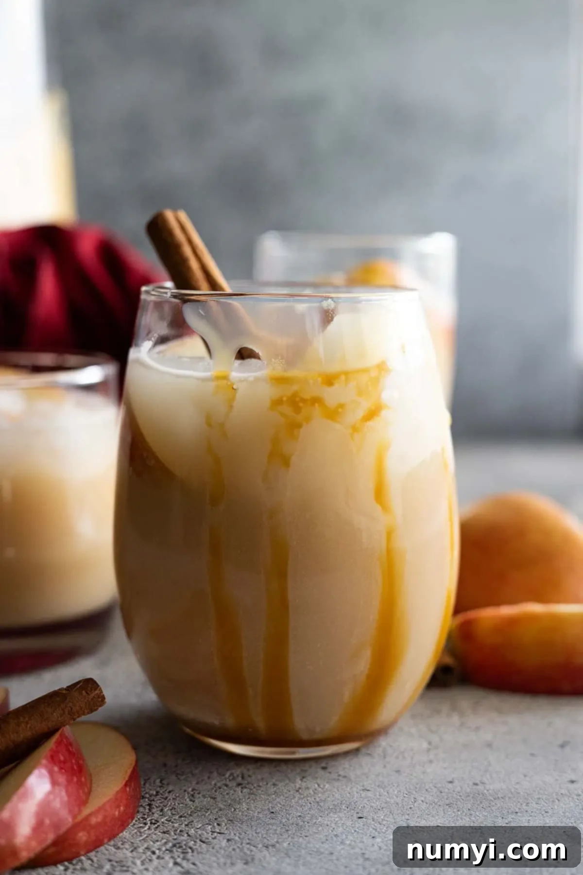 Sangria in a glass with caramel drizzle down the side. Apple slices and cinnamon stick to garnish.