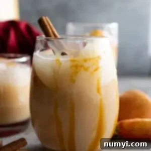 Sangria in a glass with caramel drizzle down the side. Apple slices and cinnamon stick to garnish.
