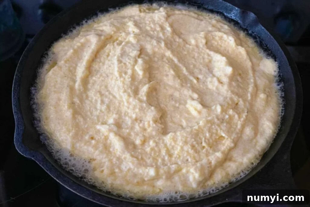 Batter mixture sizzling in a cast iron skillet.