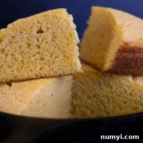 Slices of buttermilk cornbread stacked in a cast iron skillet.