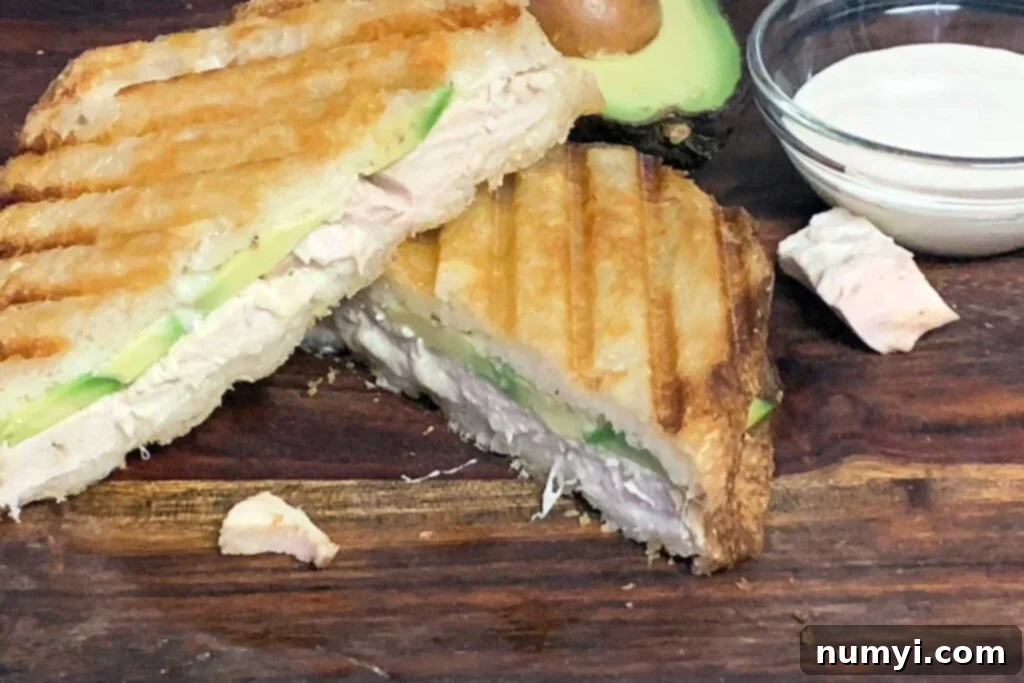 Smoked chicken panini sandwich on a cutting board.
