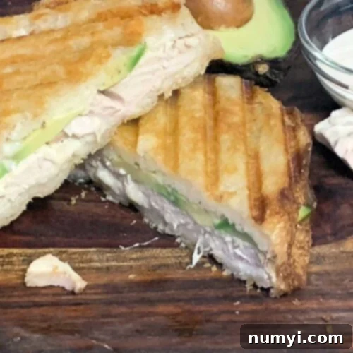 Smoked chicken panini sandwich on a cutting board.