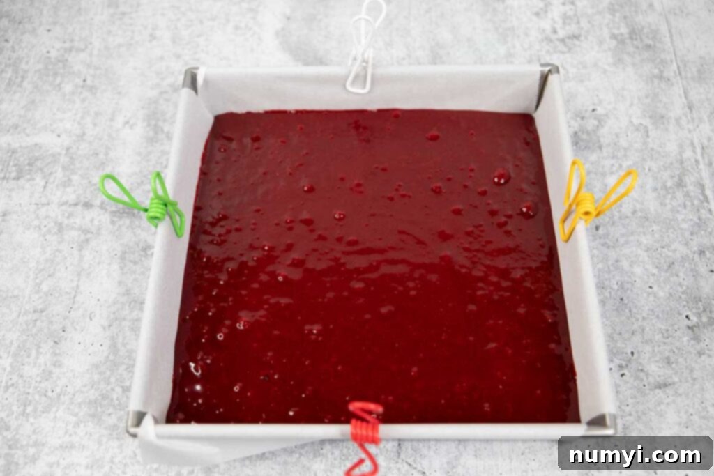 Red velvet brownie batter in a metal pan lined with parchment paper.