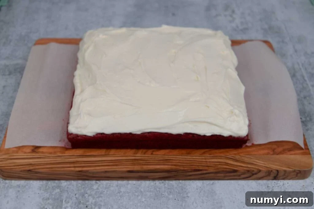 Frosted red velvet brownies on a wooden board.