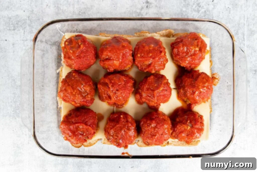 Meatballs topped with marinara on the bottom buns.