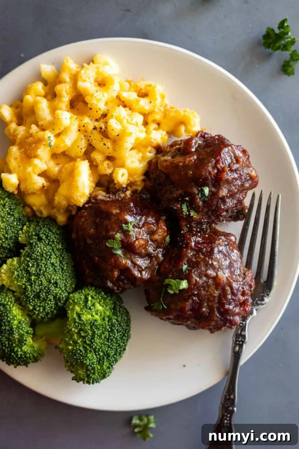 Simple BBQ Meatball Bliss 2 Delicious homemade baked BBQ meatballs served on a plate with creamy mac and cheese and steamed broccoli, perfect for a family dinner.