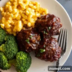 Simple BBQ Meatball Bliss 8 Close up of BBQ meatballs on a cream plate with mac and cheese and steamed broccoli.