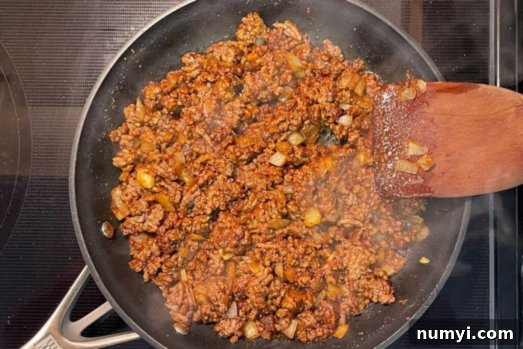 Browned beef, onions, and mexican spices in a skillet