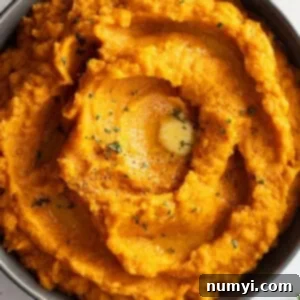 Velvety Sweet Potato Mash 8 Overhead view of mashed sweet potatoes in a dark colored bowl. Garnished with black pepper, parsley, and melted butter.