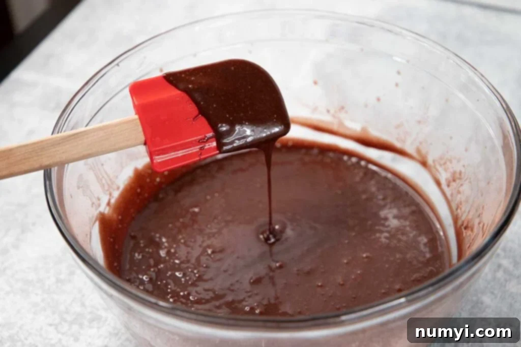 A glass bowl filled with rich, dark chocolate cupcake batter, showcasing its smooth consistency.