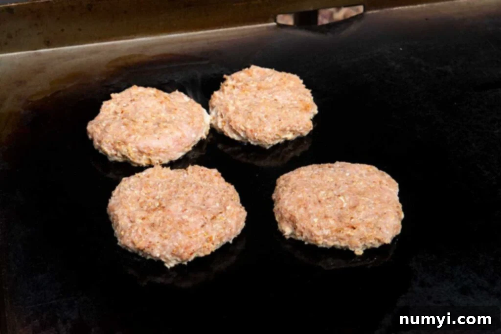 Four turkey burgers sizzling beautifully on a flat-top griddle, showcasing a perfect sear and golden-brown crust as they cook.