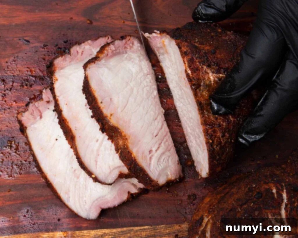 Smoked Porterhouse Pork Chops 3 Juicy slices of smoked pork from a double bone-in pork chop on a wooden cutting board.