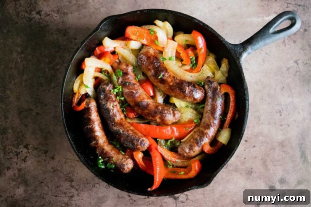Sizzling Beer Brats with Peppers and Onions 3 grilled beer brats with onions and peppers in a cast iron skillet