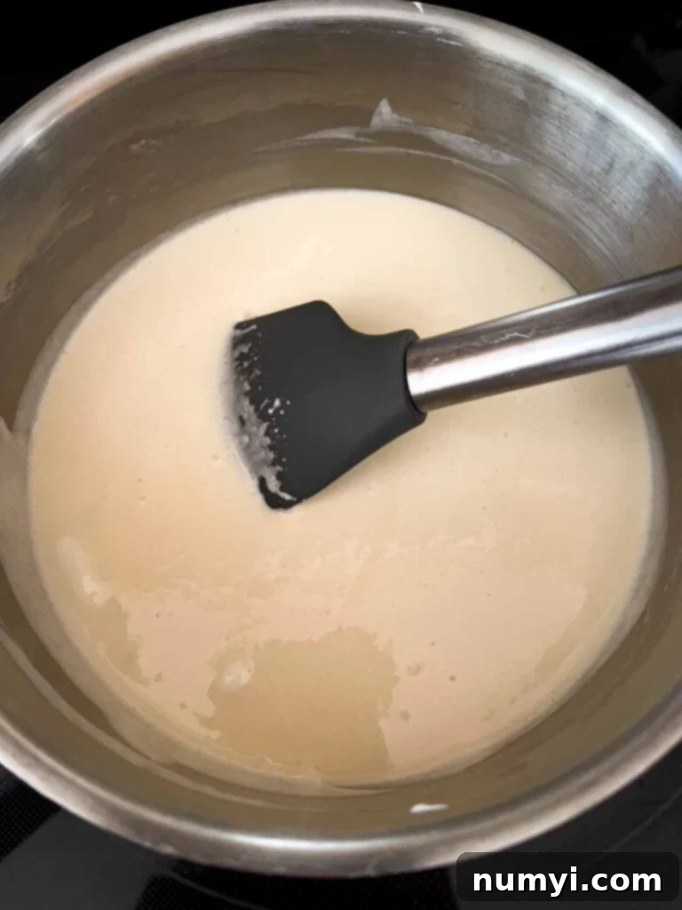 Dark chocolate fudge ingredients in a metal saucepan, showing a creamy white color before boiling, indicating the initial mixture.