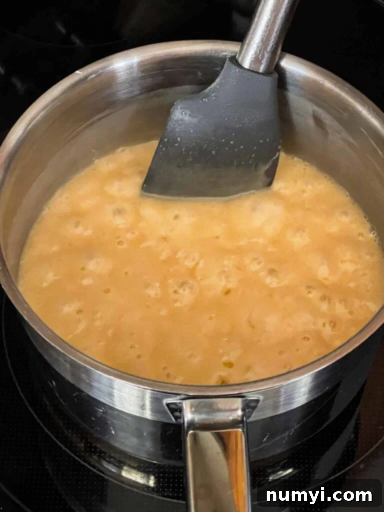 Dark chocolate fudge ingredients in a metal saucepan after boiling for 5 minutes, showing a caramel color transformation.
