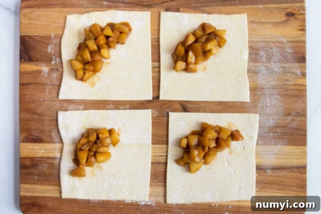 Quick & Flaky Apple Hand Pies 5 Puff pastry cut into squares with apple filling in the middle.