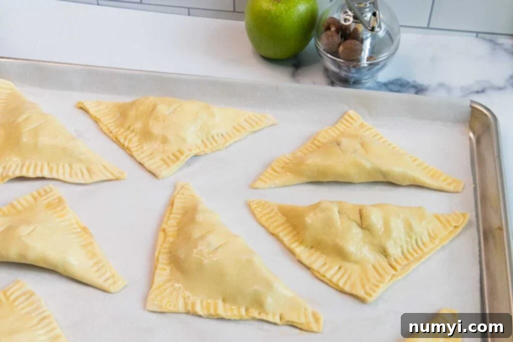 Quick & Flaky Apple Hand Pies 6 Formed apple turnovers on a baking sheet.