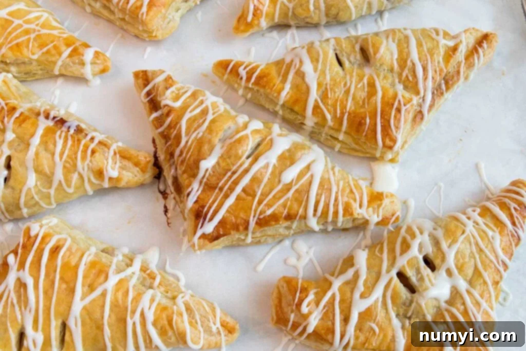 Quick & Flaky Apple Hand Pies 7 Glazed apple turnovers on a baking sheet.