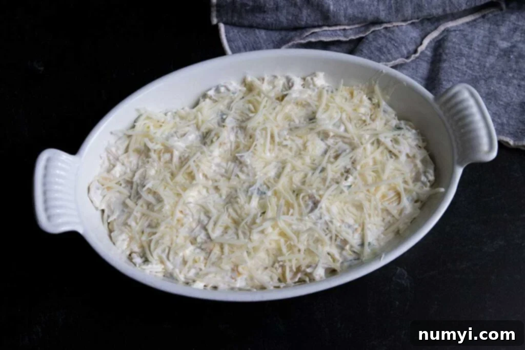 Unbaked artichoke dip mixture in a white casserole dish.