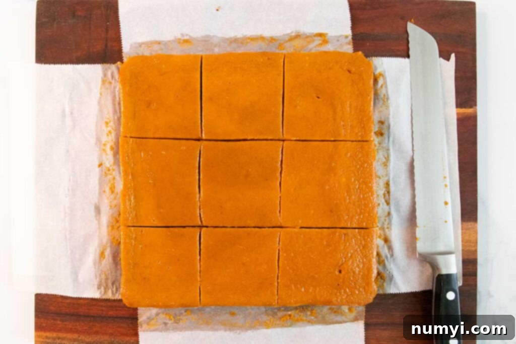 Velvety Pumpkin Spice Bars 5 Freshly baked pumpkin pie bars, cooled and sliced into squares on a wooden cutting board, ready to be served.