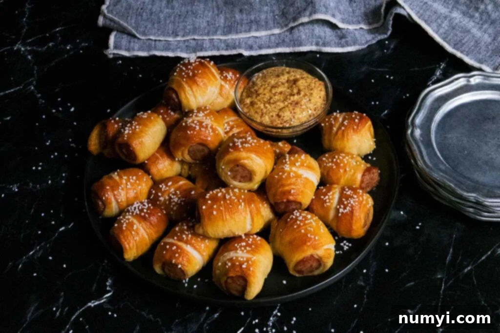 sausage pretzel bites on a black plate with serving dishes
