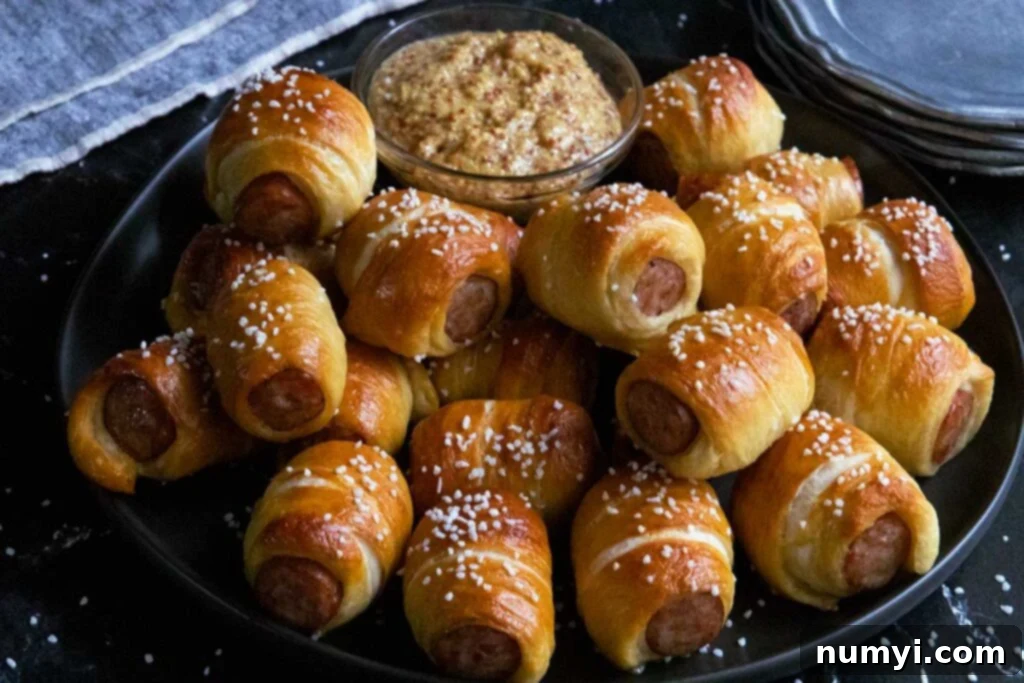 Sausage pretzel bites on a black plate with stone ground mustard garnish