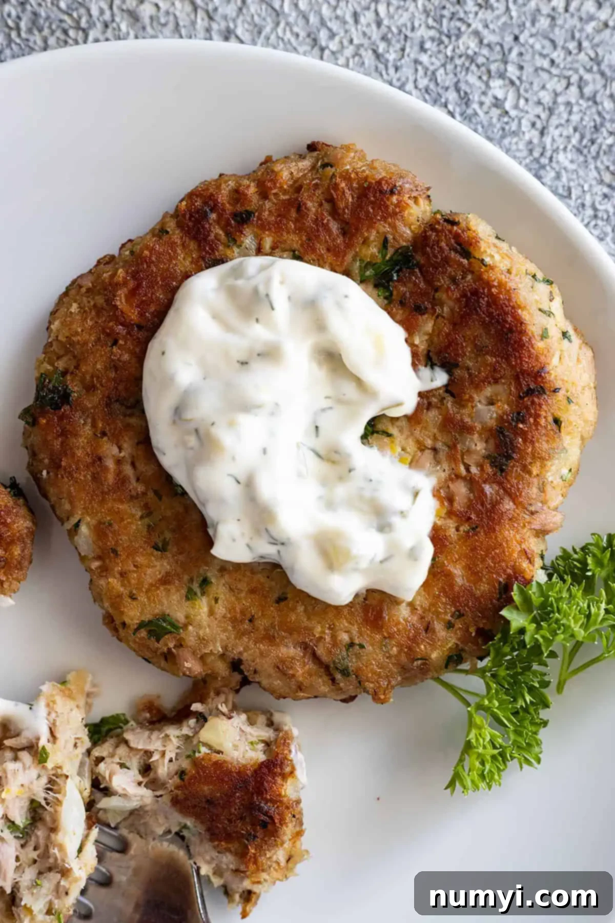 Overhead view of homemade tartar sauce on a tuna patty, ready to be enjoyed.