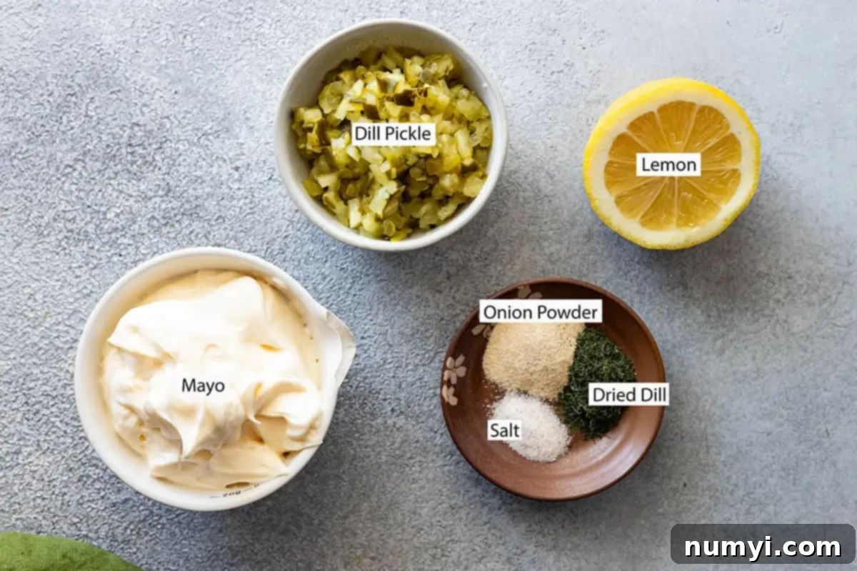 Close-up of fresh ingredients for tartar sauce: mayonnaise, dill pickles, lemon, onion powder, dried dill, and salt.
