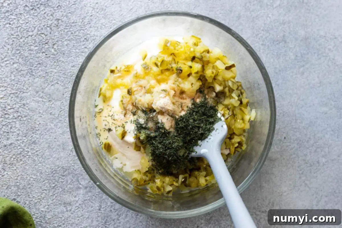 Overhead view of all tartar sauce ingredients combined in a bowl, ready to be mixed.
