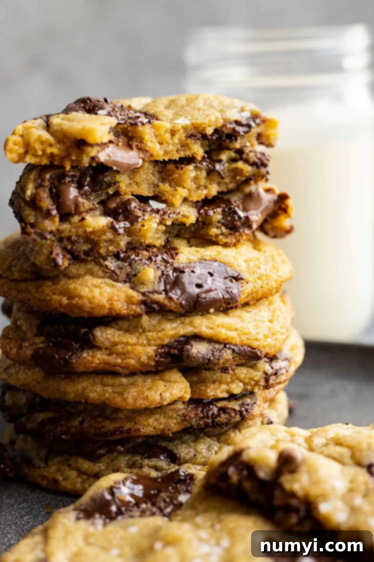 A stack of cookies. Some are broken in half to show the melty chocolate inside. 