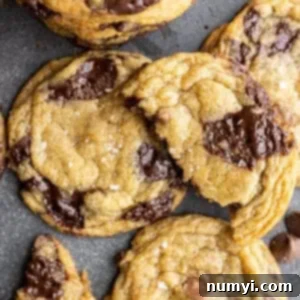 Overhead view of chocolate chip cookies. One broken in half sitting on top of the cookies.